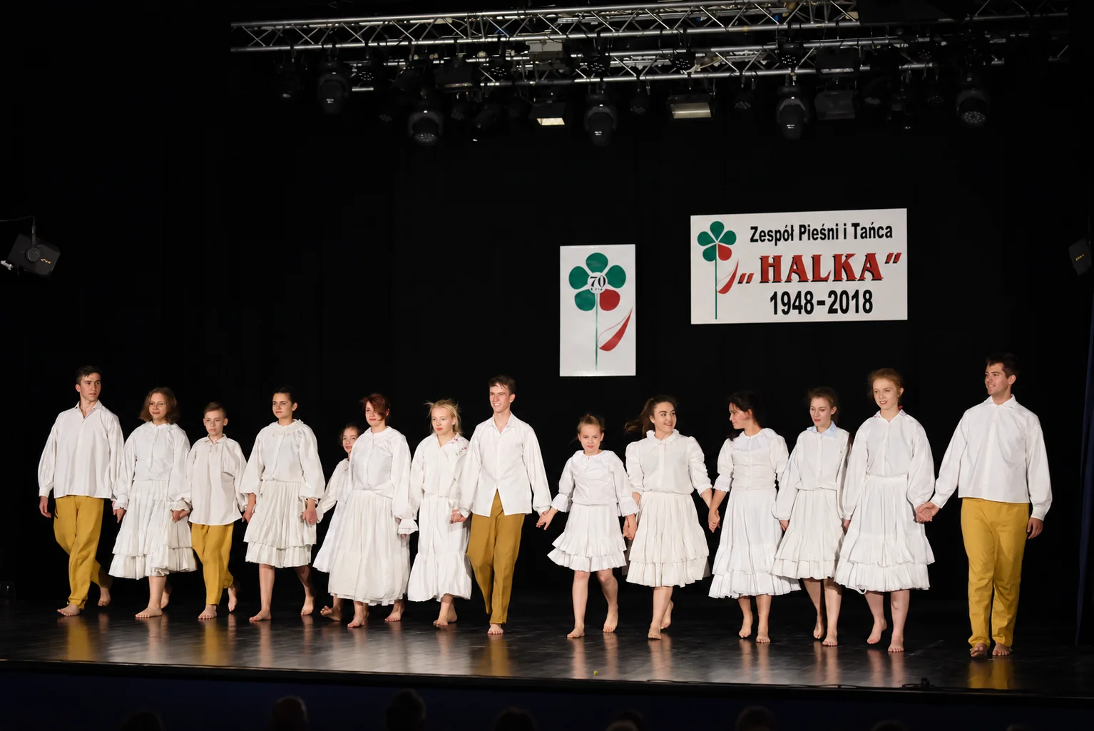 Wszyscy wykonawcy koncertu jubileuszowego Halki stoją razem na oświetlonej scenie