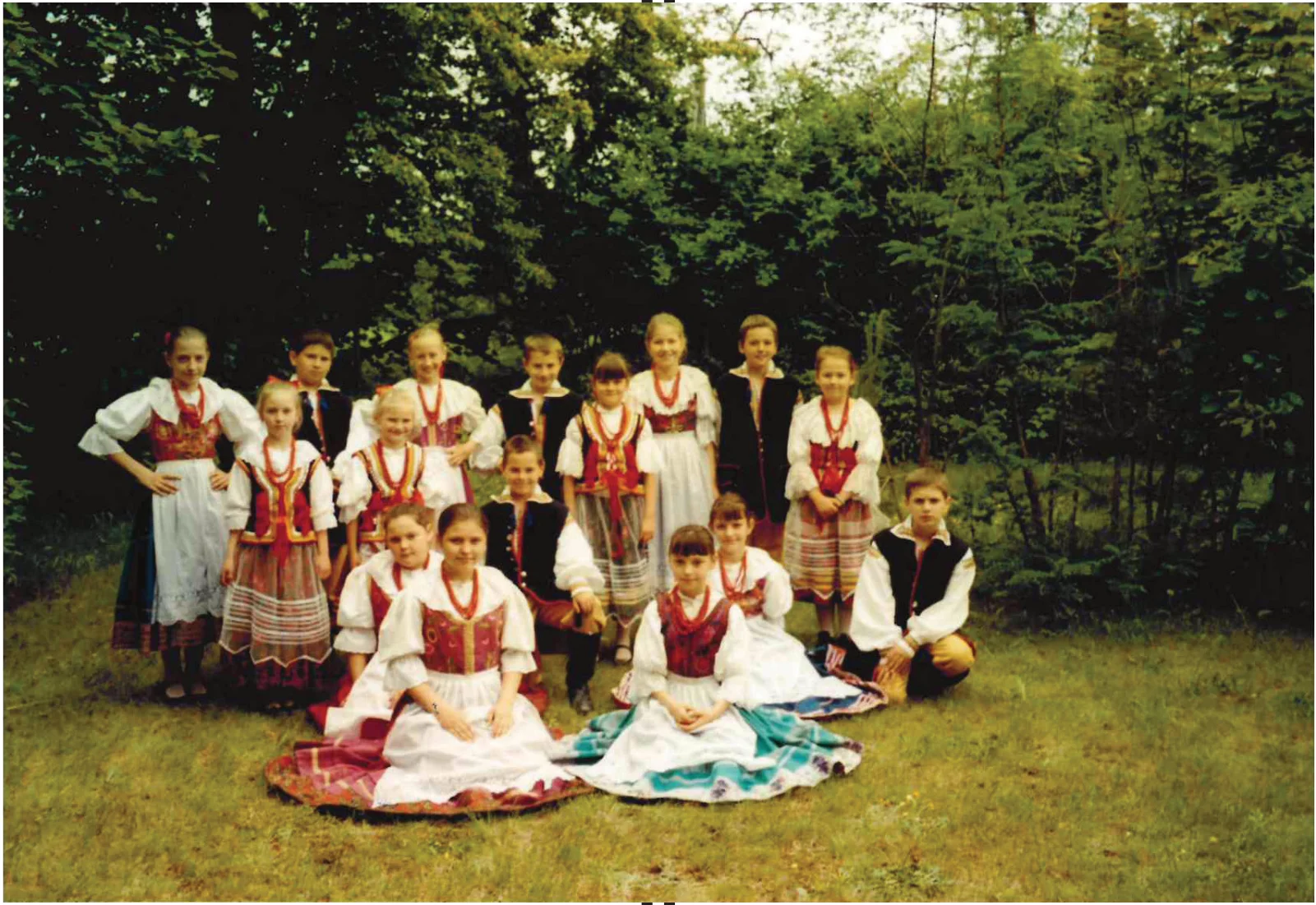 Dzieci z Małej Halki w strojach ludowych pozujące na trawie w Kokotku