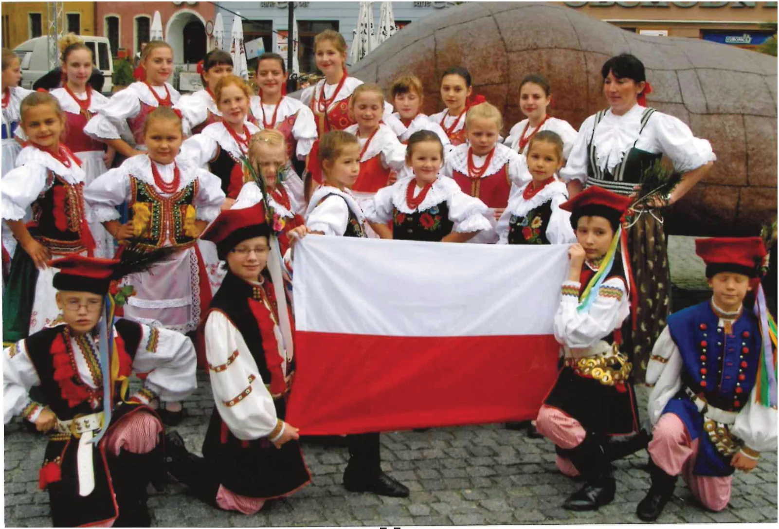 Młodzi członkowie Halki w strojach ludowych z biało-czerwoną flagą w Opawie